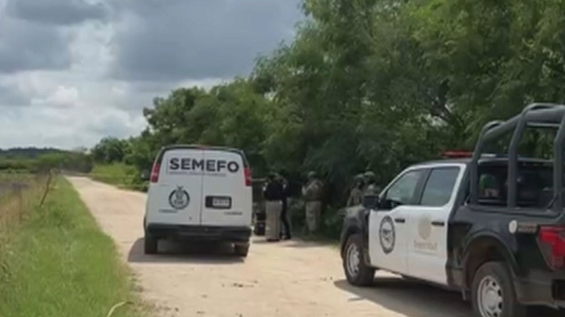 Camioneta de SEMEFO y patrulla policial estacionadas en un camino rural con personal uniformado en la escena.