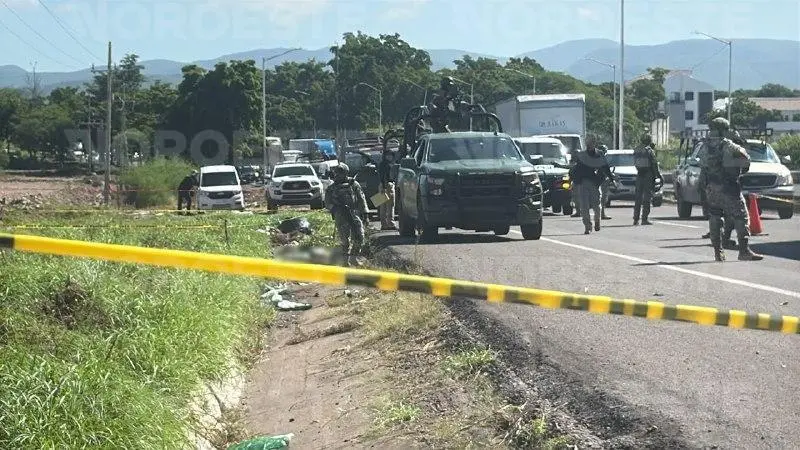 Personal militar resguarda una carretera donde se observa un área acordonada tras un hallazgo violento.